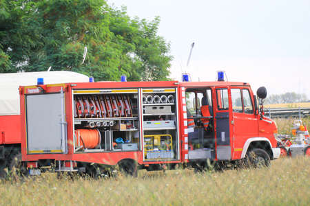 A fire engine with the side open. Lots of hoses and other equipment.