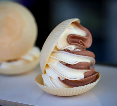 A soft ice cream with chocolate ice cream and vanilla between two waffle bowls.