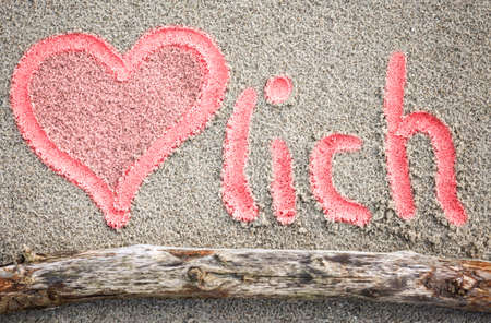 A heart drawn in the sand and the word Herzlich.