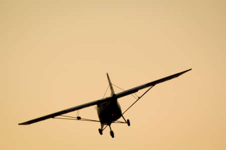 A small plane flies towards the sunset.