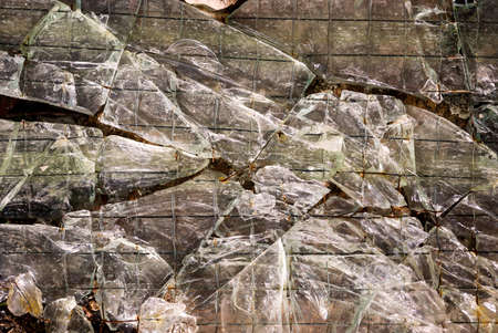 Many glass shards of a glass pane, wire glass that is broken.