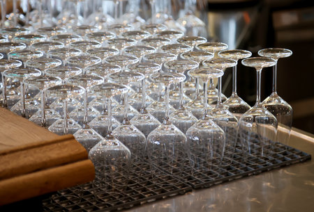 Many clean wine glasses are waiting at the counter to be filled.の写真素材
