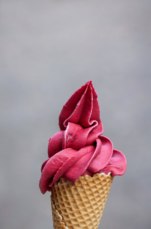Ice cream cone with pink strawberry flavor on gray background, selective focus. An ice cream cone with soft ice cream, waffle ice cream, an ice cream cone made of wafer.の写真素材