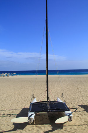 A sailing catamaran lies on the beach far from the water.の写真素材