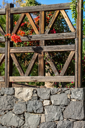 A wooden gate with flowers on the background of the stone wall.の写真素材