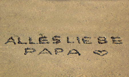 Message laid in sand with stones, â€œAll the love Dad.â€
