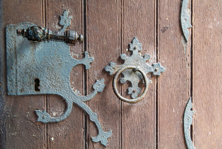 An old door lock with handle on an old wooden door. Old wooden door with lock and keyhole, closeup of photoの写真素材
