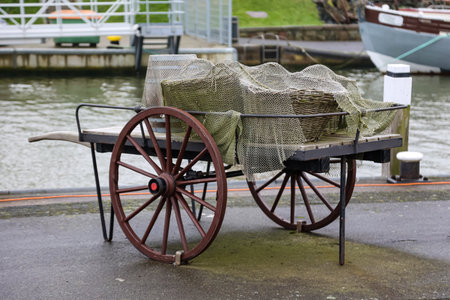 Old utensils from a fish market. Wooden cart with fishing net on the background of the canal.の写真素材