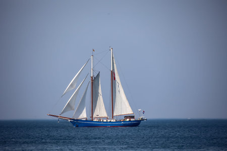Sailboat in the sea on a background of blue sky.