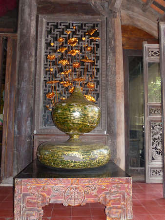 two belly vase with golden flowers on old table with ornamentsの写真素材
