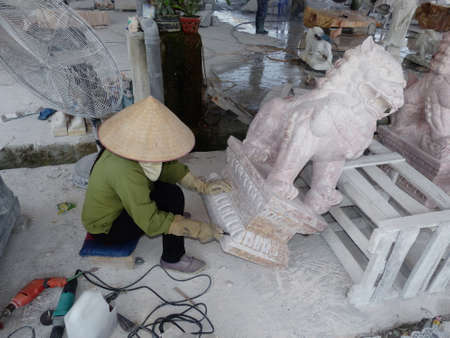 stonemason woman with  boater working on dragon statueの写真素材