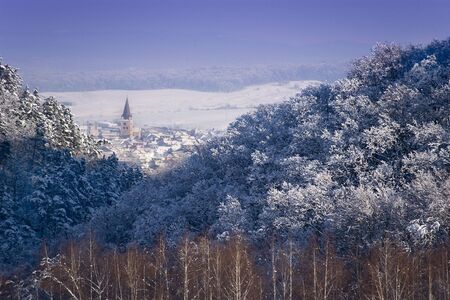 winter landscape forest transylvanian village and church tower sunny dayの写真素材
