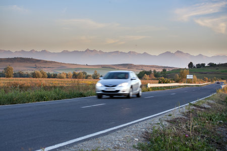 Blurred car traveling on road with beautiful mountain ridge landscape in Transylvania Romaniaのeditorial素材