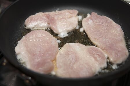 Turkey breast cooking in pan in butter on gas stoveの写真素材