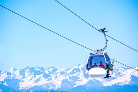 Generic ski gondola lift in Alps mountain ski resort, skier inside, on clear winter day