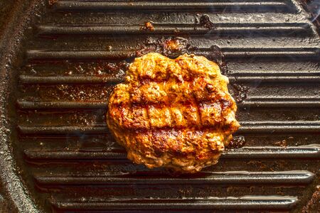 Beef burger fried in grill pan on stovein the kitchen, live cooking smokeの写真素材