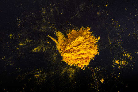 Contrasting yellow heap of curry powder on black slate backgroundの写真素材