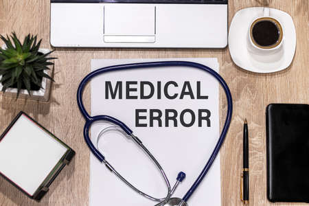 Stethoscope on notebook and pencil with Medical Error words as medical concept.
