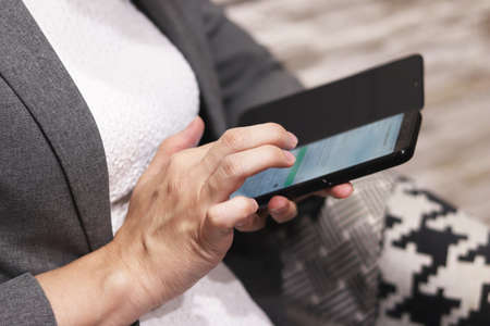 Women sitting in a coffee shop using a smart phone for talking, reading and sending messagesの写真素材