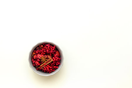 Red nuts and cones, spice in a gray bowl on white background. Christmas concept. Selective focus. Top view.の写真素材