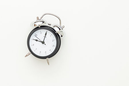 Classic black table clock isolated on a white background, view from above. Selective focus. Top...