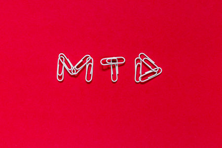 The word is written with paper clips on a red background. Care concept.