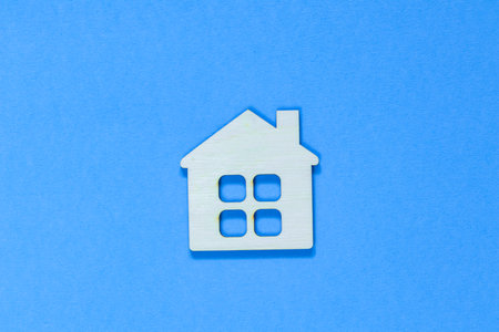 Figurine of a wooden house on a dark blue background. Concept of real estate, home purchase and sale. Affordable housing at a low price. Home for the family. Stay at home concept.の写真素材