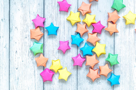 Multicolored origami paper star on white wooden backdround. Top view.の写真素材