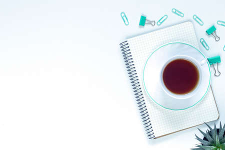 flat lay composition with notebook, pen, coffee, plant on white background. Concept remote study and work at home, freelance, quarantine, office table, coffee break. Distance learning. Copyspaceの写真素材