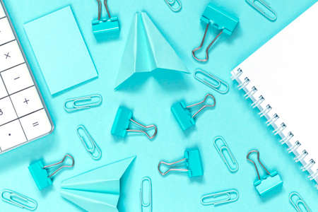 Back to school concept. School and blue and white office supplies on blue office table. Flat lay. Blue paper airplane ahd paper.の写真素材