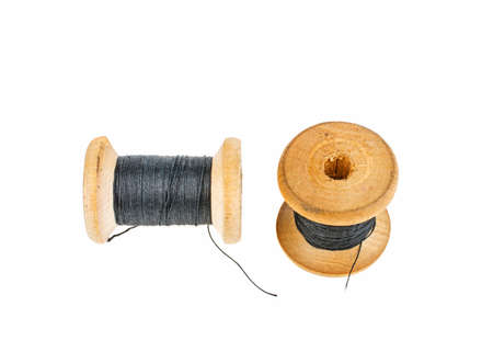 Wooden spool with black thread on a white backgroundの写真素材