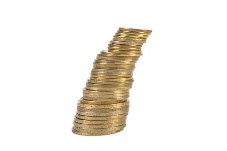 coins of yellow metal, of different denominations stacked tower tilted to the right on a white...