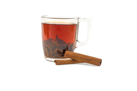 tea in a glass cup and two cinnamon sticks isolated on white background