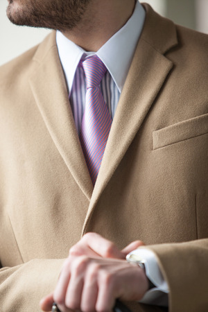 Close up of businessman in beige coat, white chemise with stripes and pink tie の写真素材