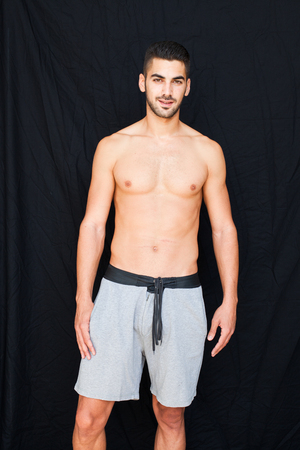 Handsome man half naked smiling on black backgoundの写真素材