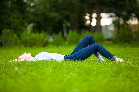 Beautiful healthy Young Woman lying and relaxing on the green grassの写真素材
