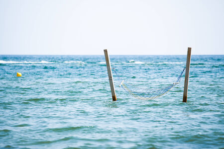 Hammock hanging over sea waterの写真素材