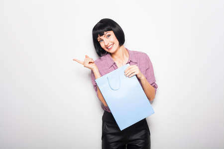 nice young woman with a shopping bag in hand, pointing and looking in side directionの写真素材