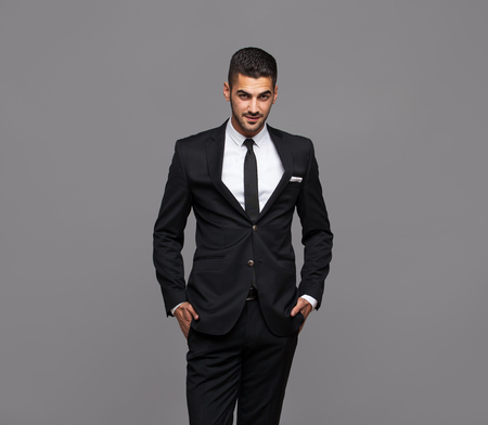 handsome hispanic elegant man in black suit on grey backgroundの写真素材