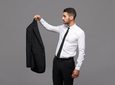 handsome hispanic elegant man in black suit on grey backgroundの写真素材