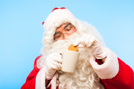 santa claus soften biscuit in a cup of milkの写真素材
