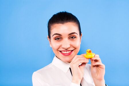 young beautiful woman on office outfitt with a duck in her hands , on blue backgroundの写真素材
