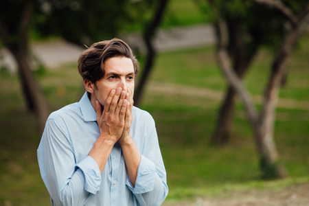 portrait of a man in blue shirt standing outside in parkの写真素材