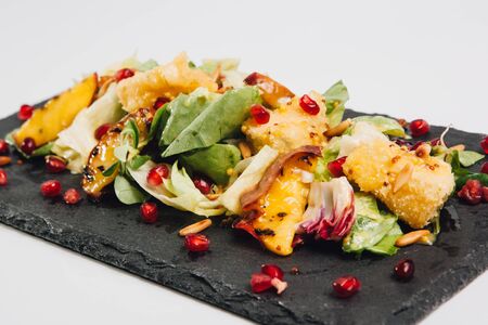 salad with pomegranate and cheese on blue dishの写真素材