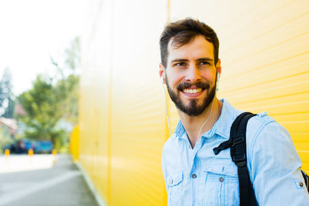 handsome student with bakpack and a book on yellow backgroundの写真素材