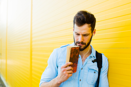 handsome student with bakpack and a book on yellow backgroundの写真素材