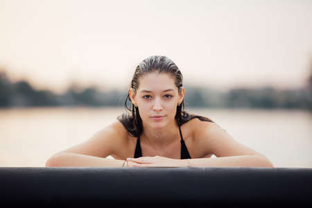 wet natural woman standing in water on a paddle board, lake surrounded by treesの写真素材