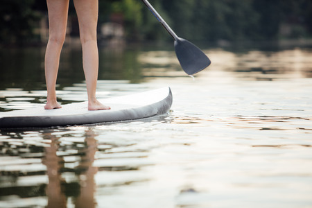 clouse-up of a woman legs on paddleboard in water