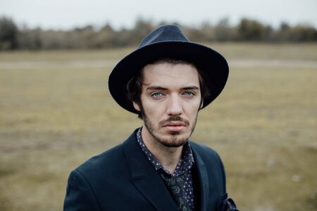 portrait of a handsome stylish man posing on a green field with cool clothesの写真素材