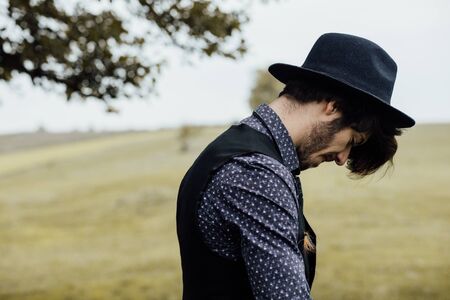 handsome stylish man posing on a green field with cool clothes